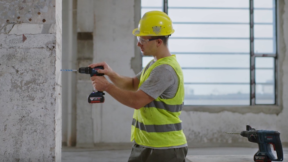 Tôi có thể tải ứng dụng BeConnected ở đâu?  Một người thợ thủ công đang khoan vào tường bằng máy vặn vít không dây Bosch Professional.