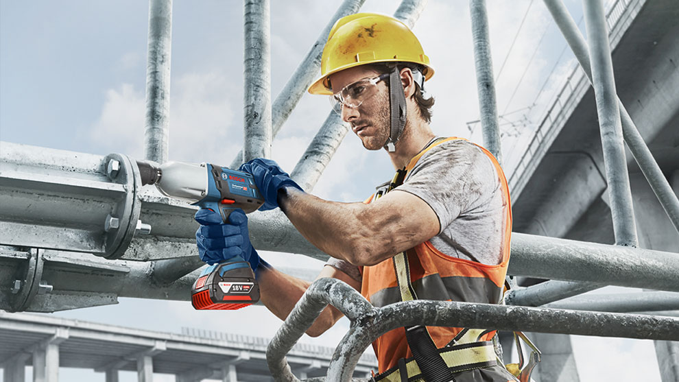 Một công nhân đội mũ bảo hiểm màu vàng đang sử dụng máy Bosch Professional.
