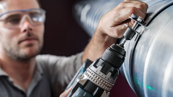 Dầu khí Một người thợ thủ công sử dụng tua vít không dây Bosch Professional trên một đường ống.