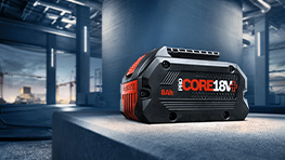 Một pin Bosch Professional CORE 18V được đặt trên một bề mặt màu xám.