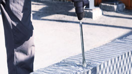 Một thợ thủ công đang sử dụng một chiếc khoan Bosch Professional trên một viên gạch.