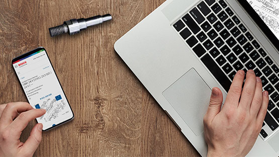 Một chiếc smartphone và một chiếc laptop nằm trên một cái bàn gỗ, bên cạnh là công cụ.